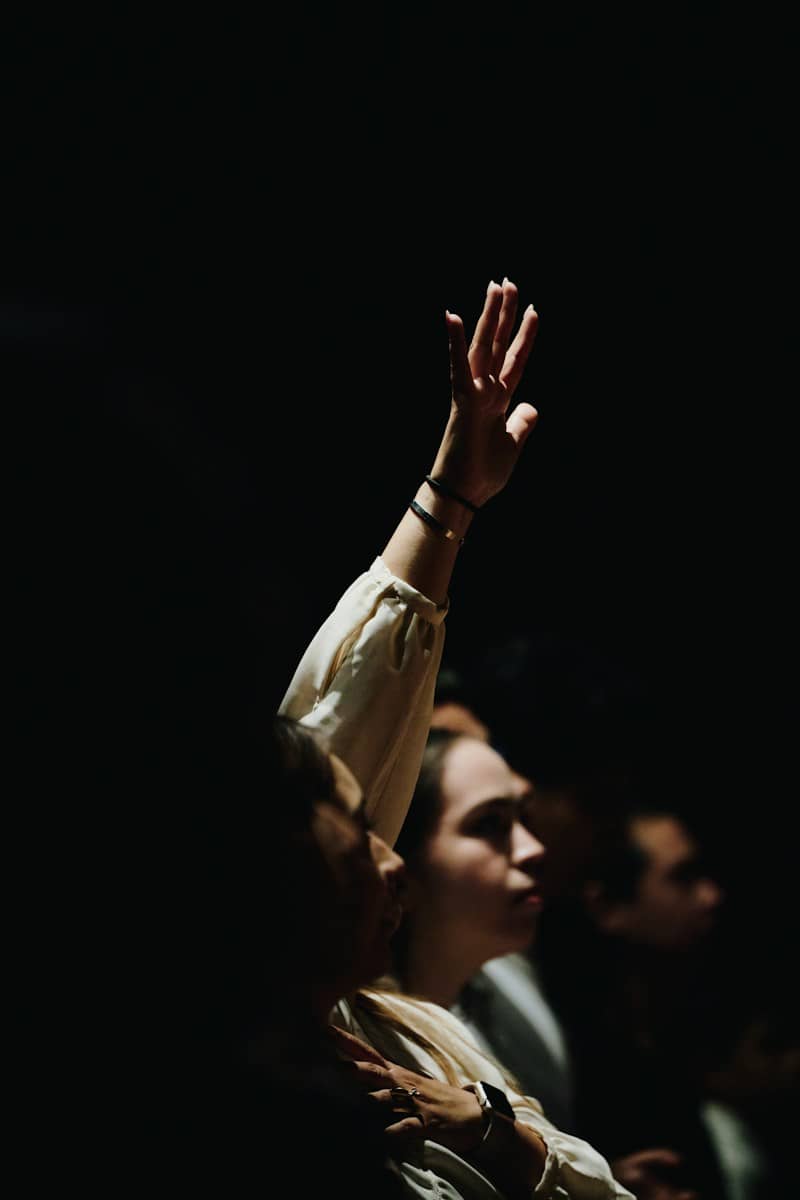 A person with a raised hand in a dimly lit room