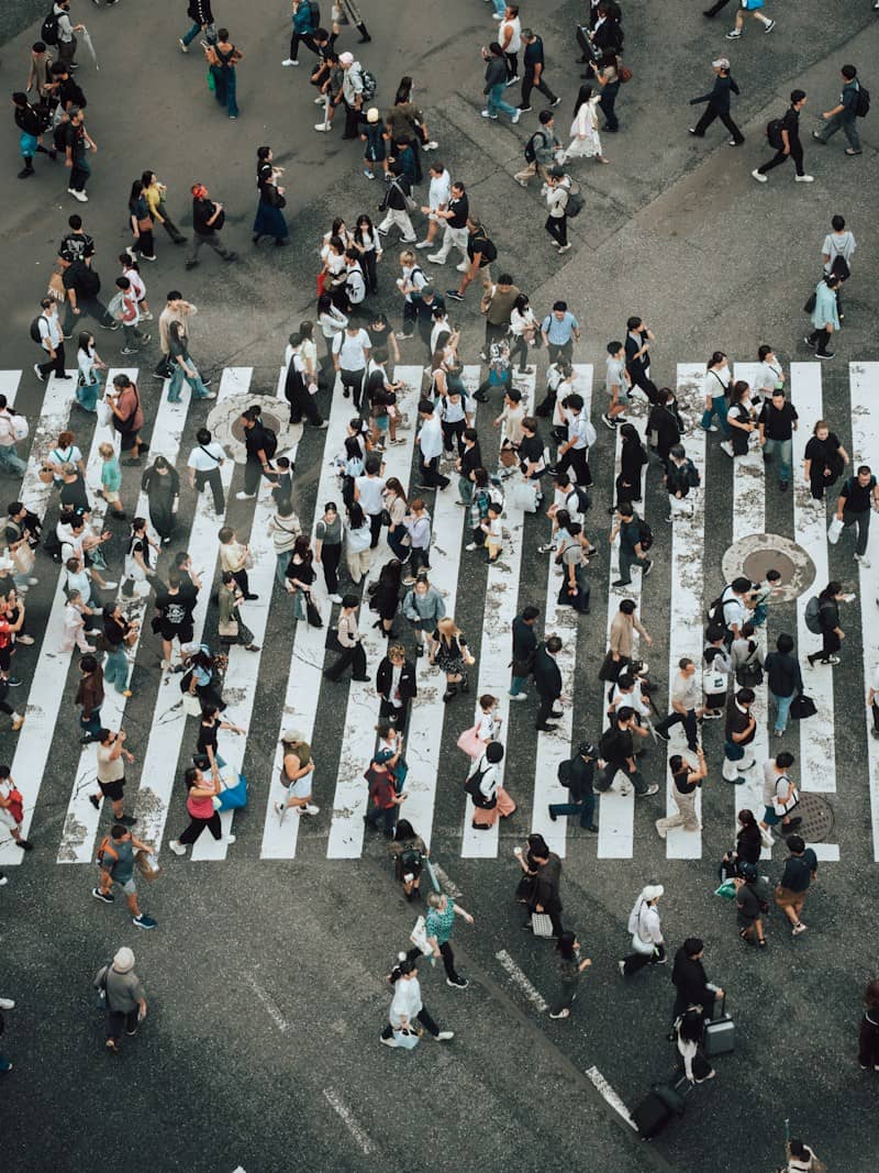 A large group of people crossing a wide pedestrian crosswalk in a city