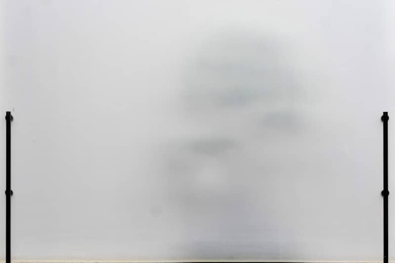 A blurry figure behind a translucent white screen.
