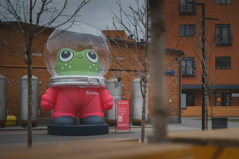 An inflatable green frog in a space suit on a city plaza