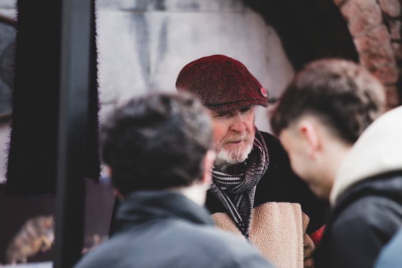 Man in a flat cap talking to two younger men