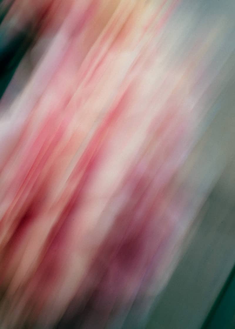 Abstract motion blur with pink, red, and white streaks.