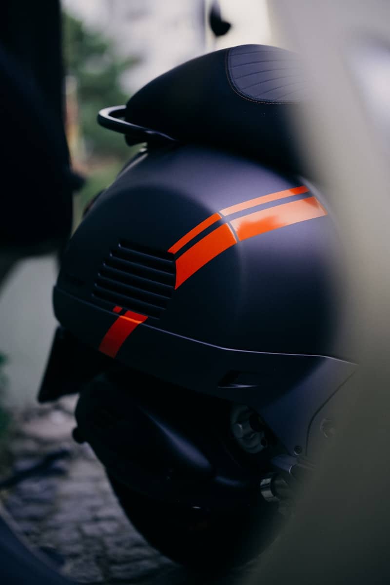 Rear view of a matte dark grey scooter with bright orange racing stripes