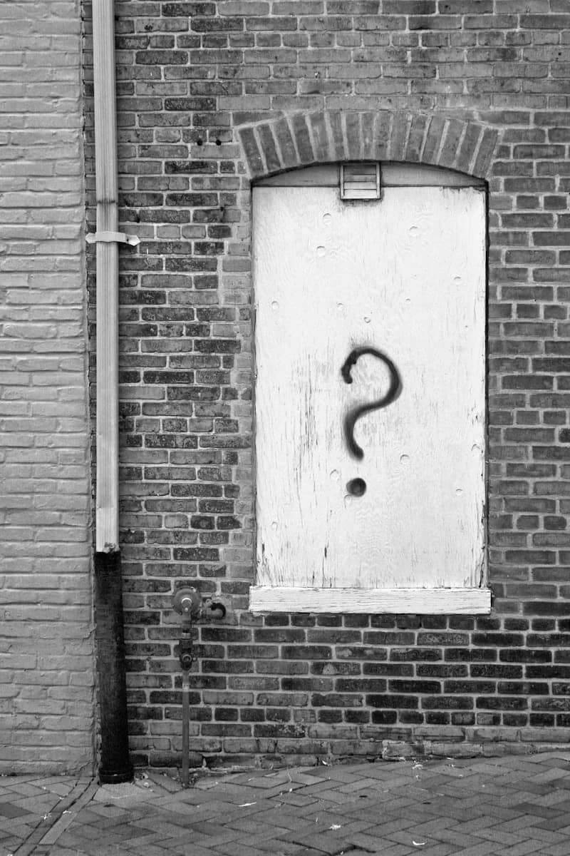 A black and white photo of a door with a question mark on it