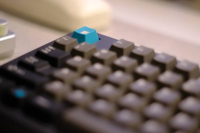 Computer keyboard with a single bright blue key.