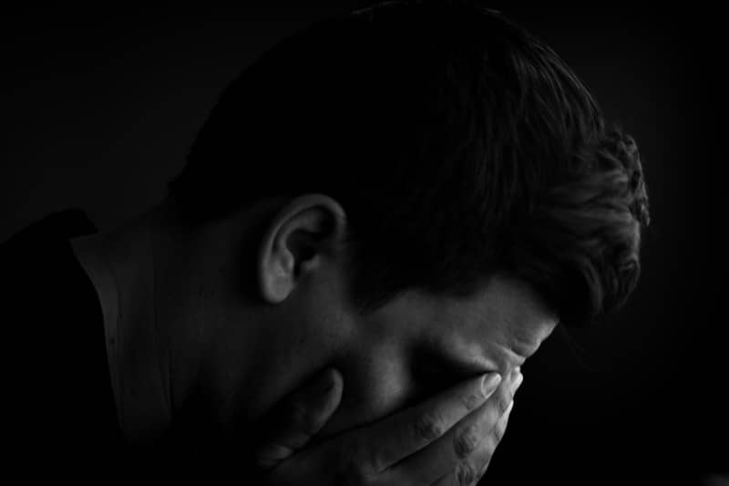 Man with head in hands in dark