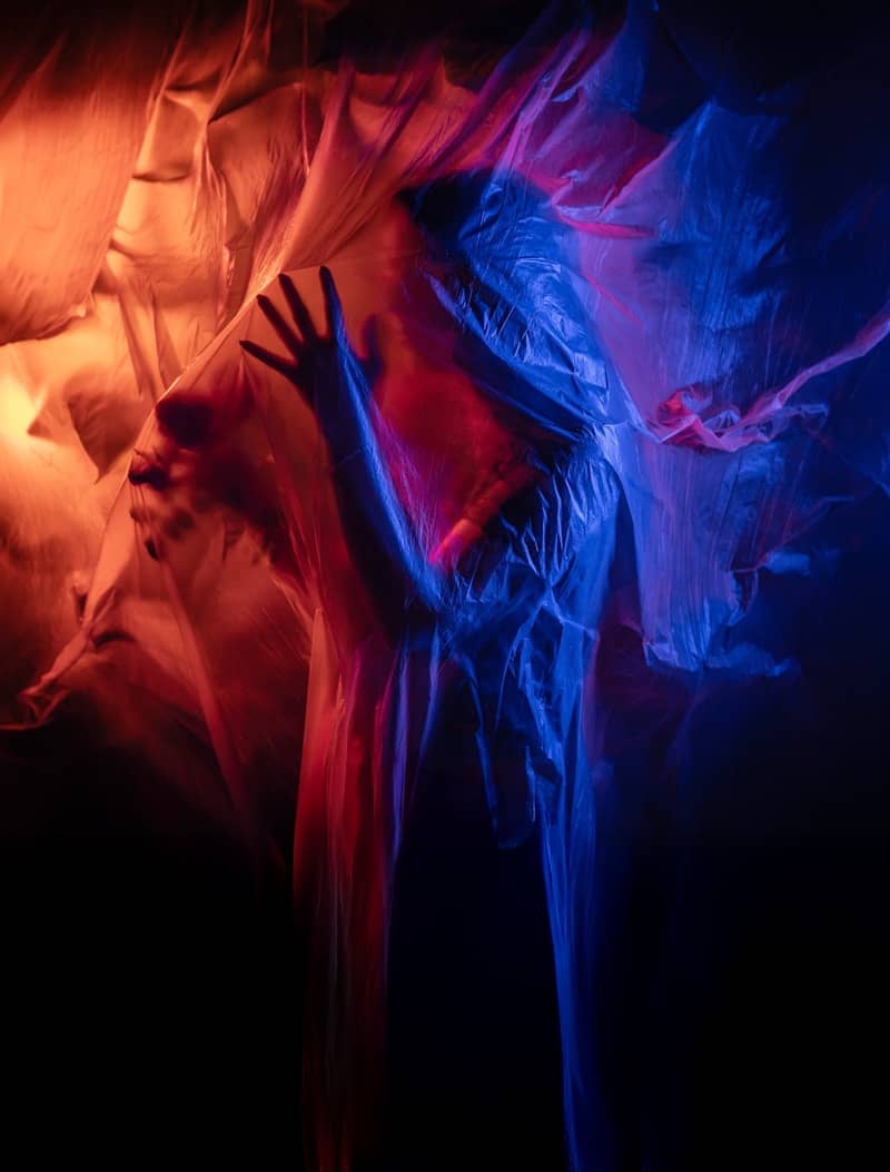 Figure shrouded in translucent fabric with red and blue lights