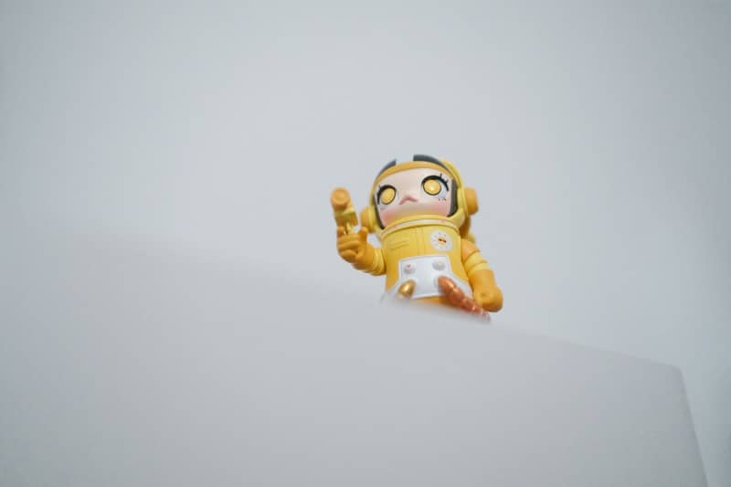 A small yellow astronaut toy peeking over a surface