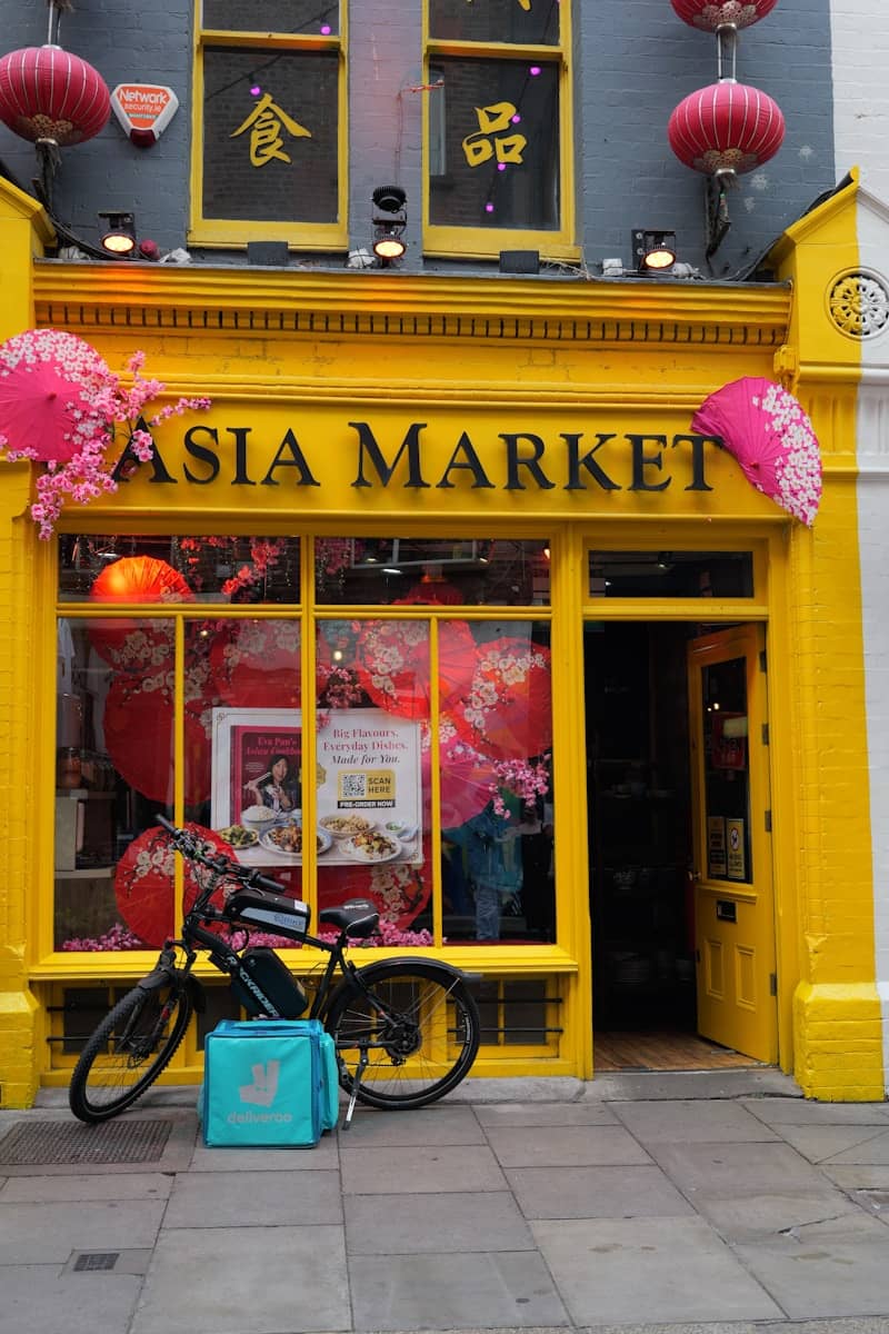 Bright yellow asia market storefront with bicycle and delivery bag.