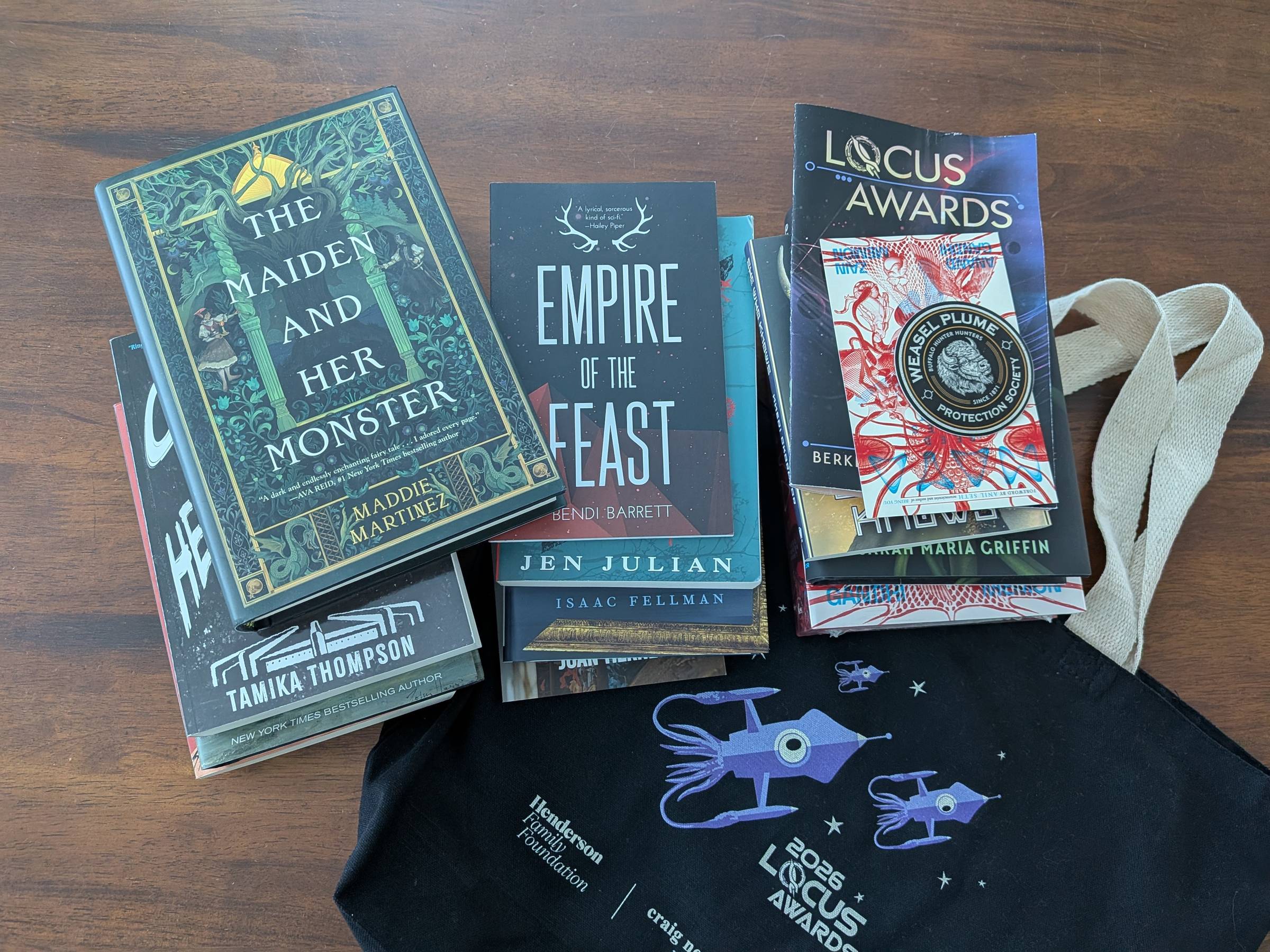 A dozen SFF books on top of a Locus-branded tote bag
