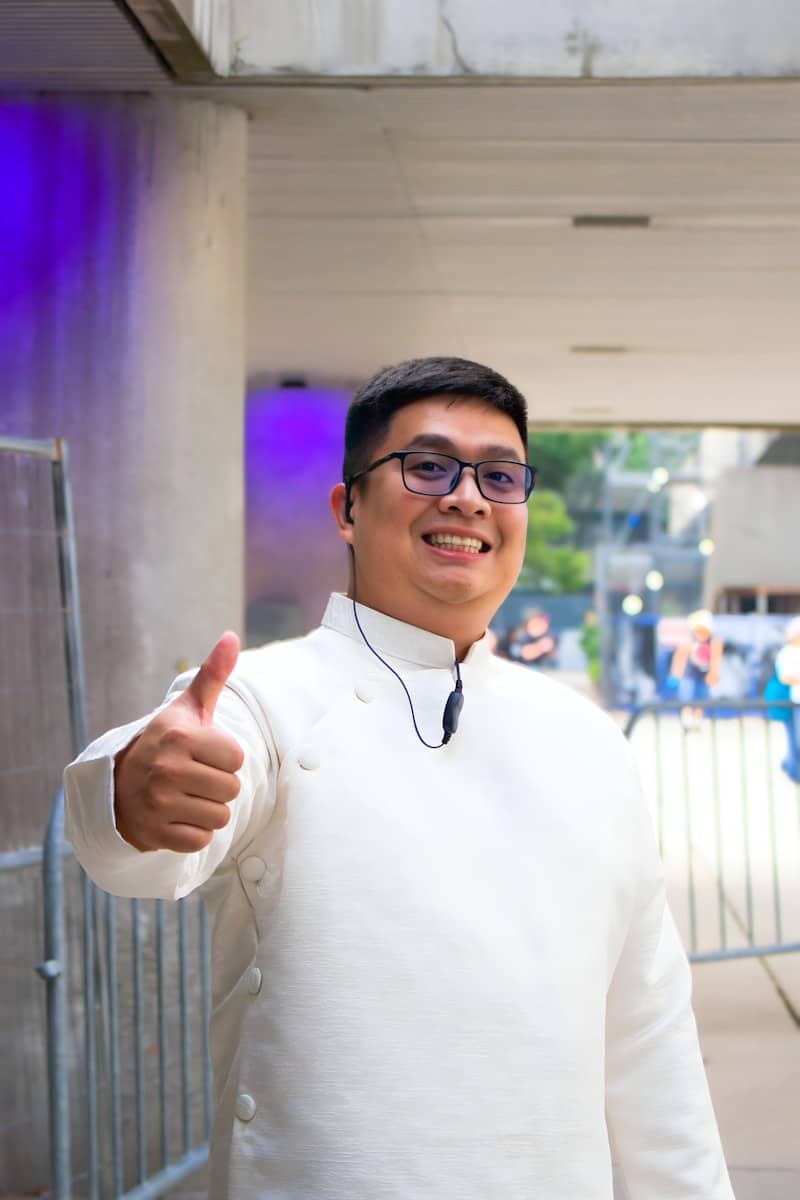A man in a white shirt gives a thumbs up.