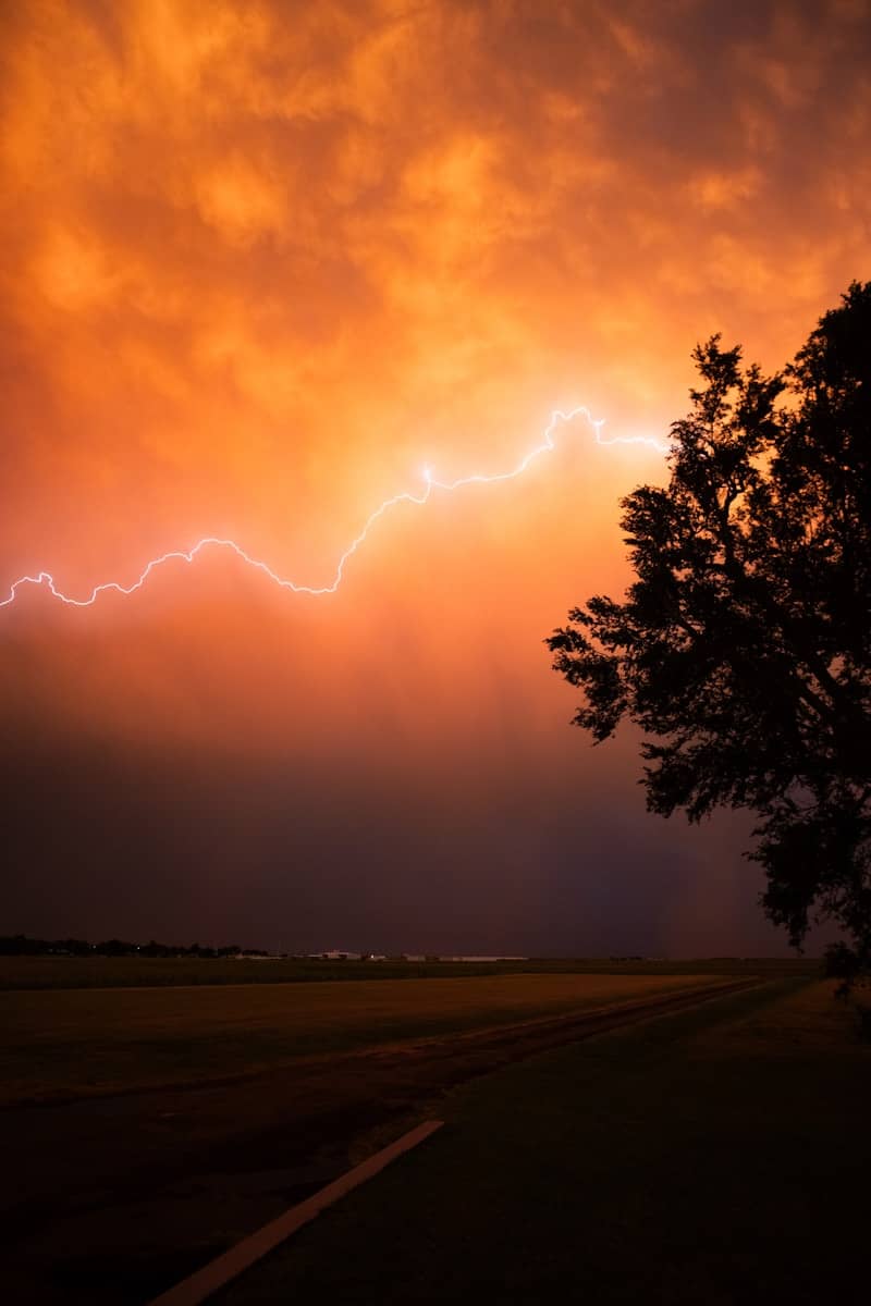 Lightning strikes across a dramatic orange sky.
