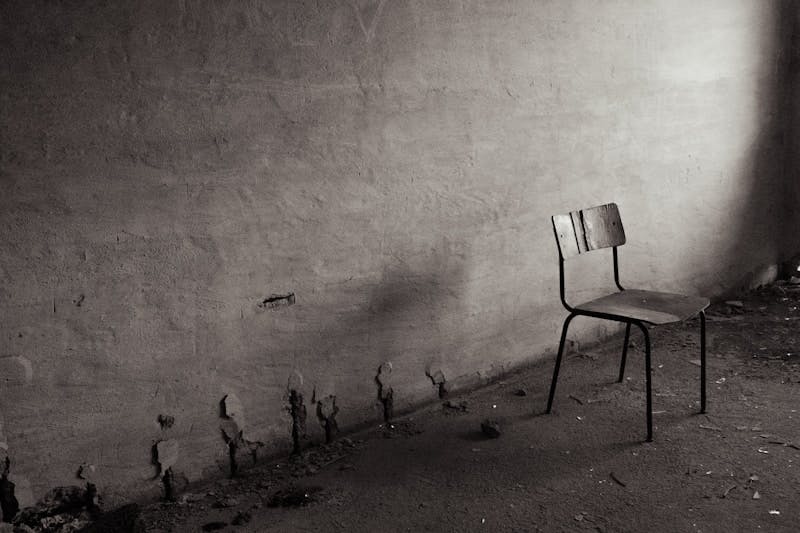 A black and white photo of a chair next to a wall