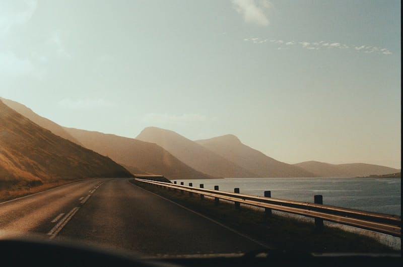 A car driving down a road next to a body of water