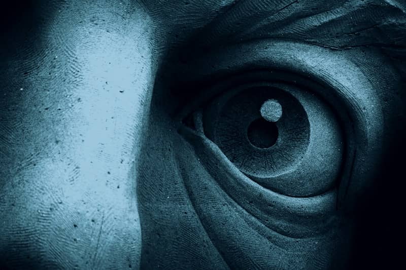 A close-up of a sculpted eye with textured blue stone surfaces