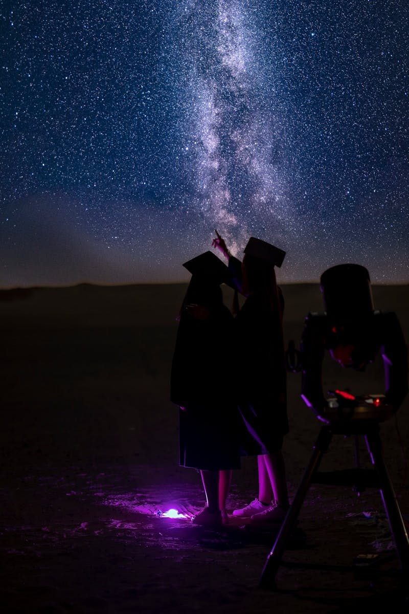 a couple of people standing next to each other under a sky filled with stars