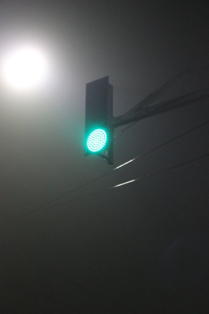 A green traffic light on a foggy night