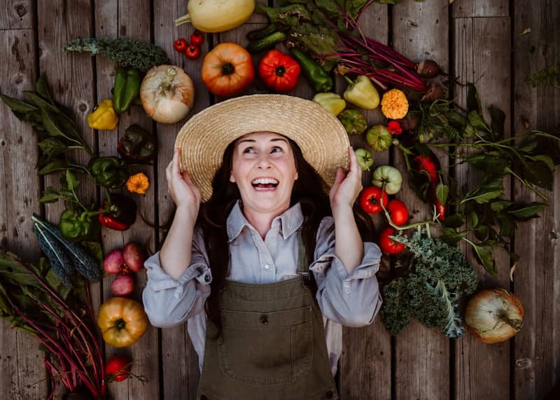 A woman wearing a straw hat surrounded by fruits and vegetables