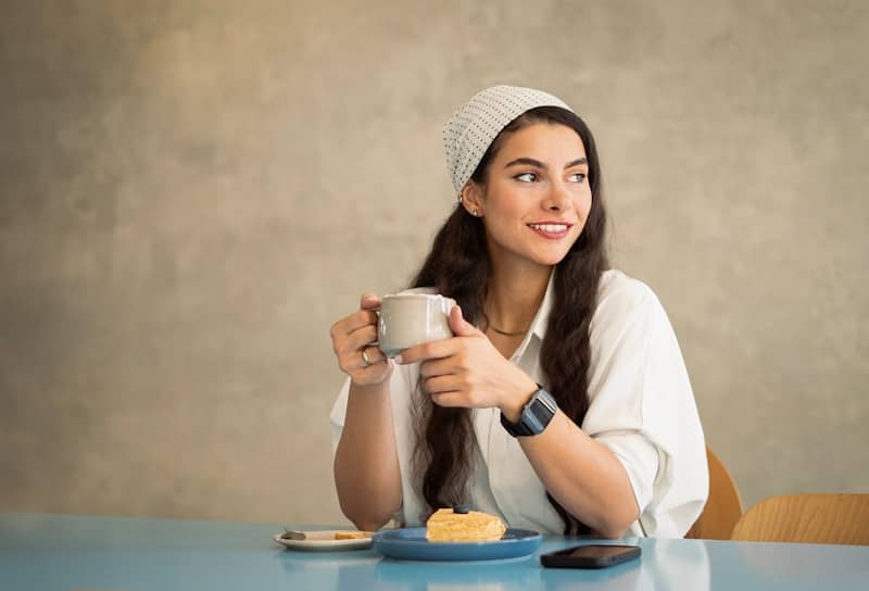 A woman sitting at a table with a cup of coffee