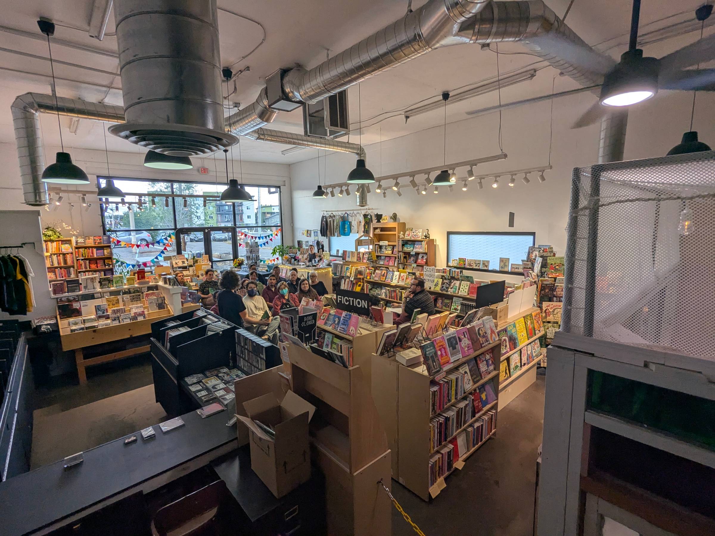 Another shot of the bookstore, where shelves are set up with an audience toward the front of the store and the speakers (Naseem and Griffin) in the middle of the shelves.