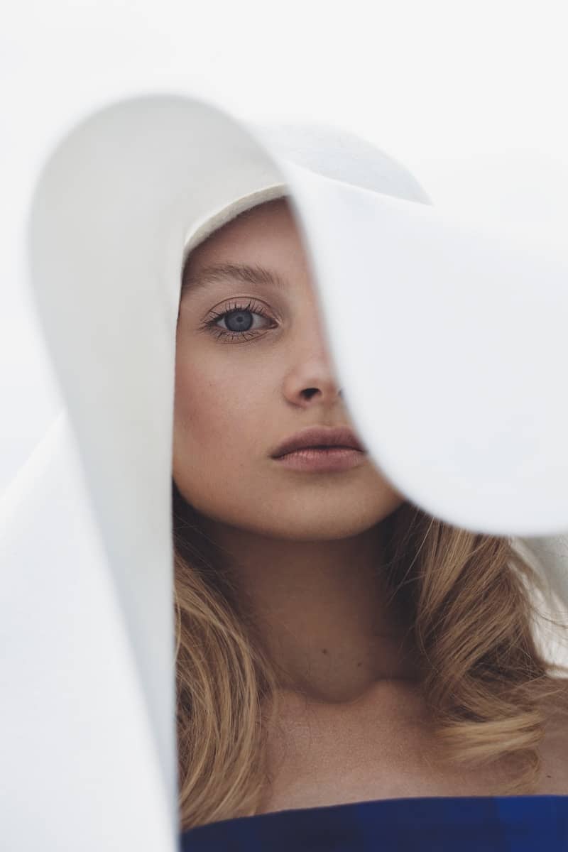 Young woman with blonde hair wearing a large white hat.
