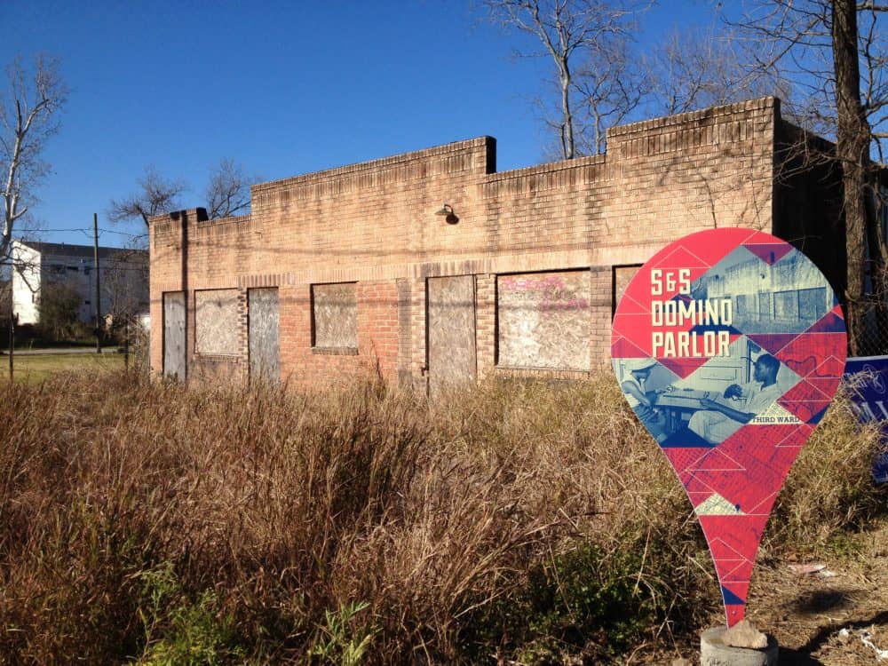 Teardrop-shaped marker reading “S&S Domino Parlor” in front of an abandoned brick building in Houston’s Third Ward, part of the Animating History public art project.