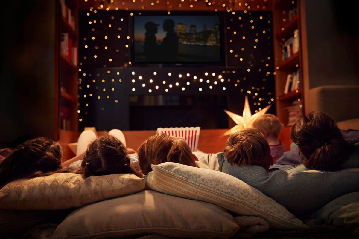 family laying on couch (view of back of their heads) watching a movie 