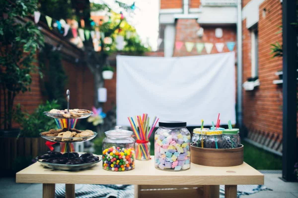 backyard set up with homemade movie screen with table in front with snacks and sweets