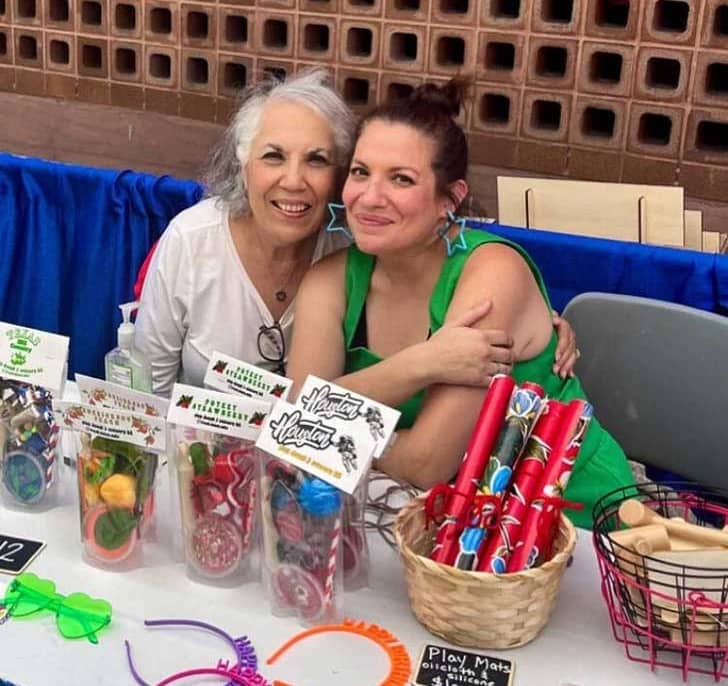 Two people sitting at a table with packaged kits and other items on the table