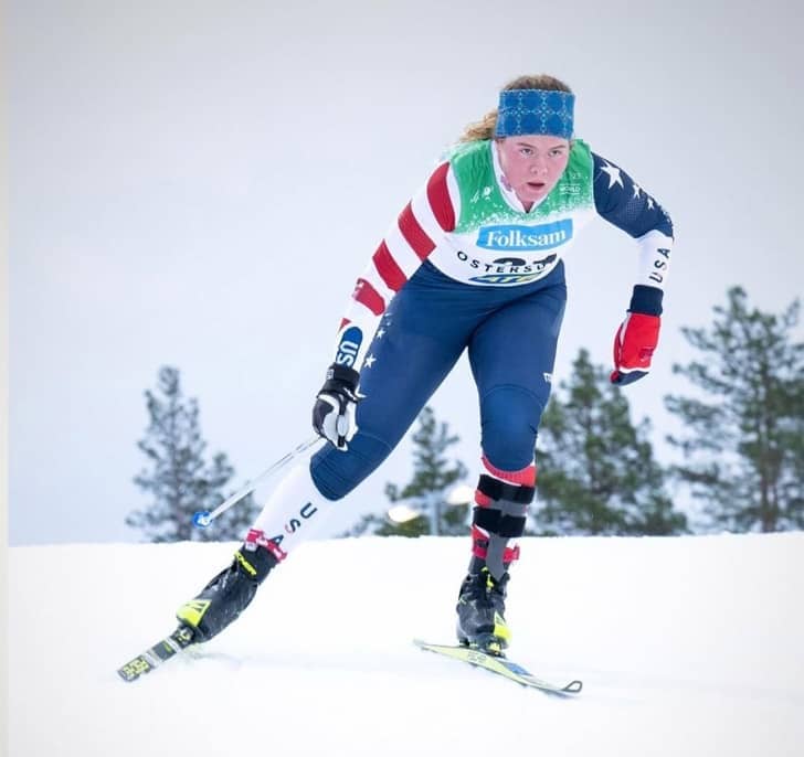 Person Nordic skiing in a USA uniform, right hand is holding a pole
