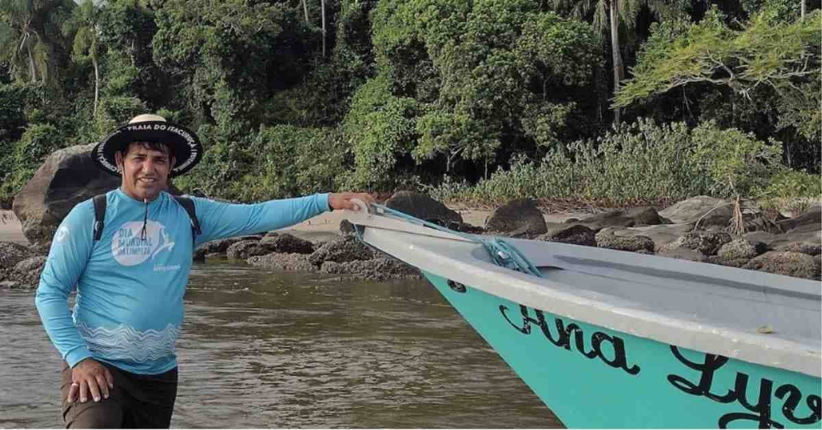 A person in a blue long sleeve shirt standing at the bow of a teal-colored boat