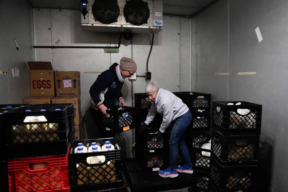 Two people stacking crates in a refrigerated room