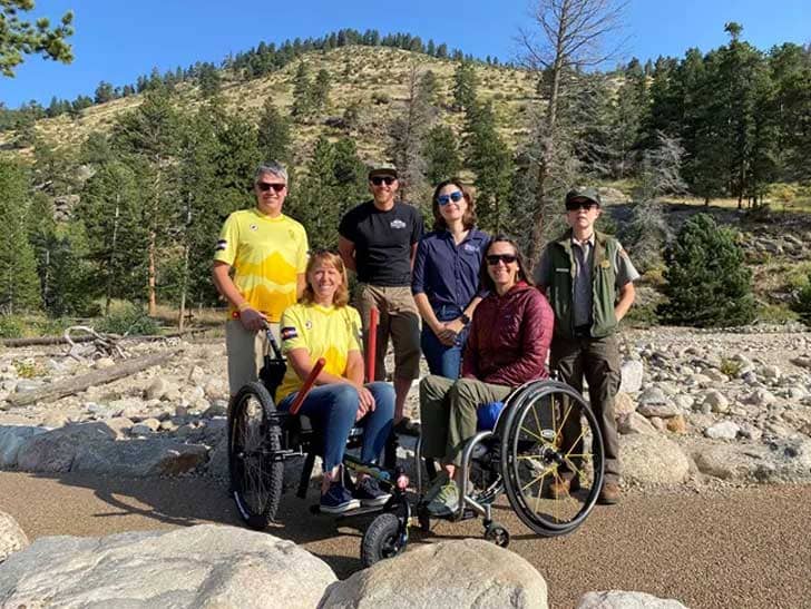 Six people with Rocky Mountain National Park in the background, two are in a wheelchair