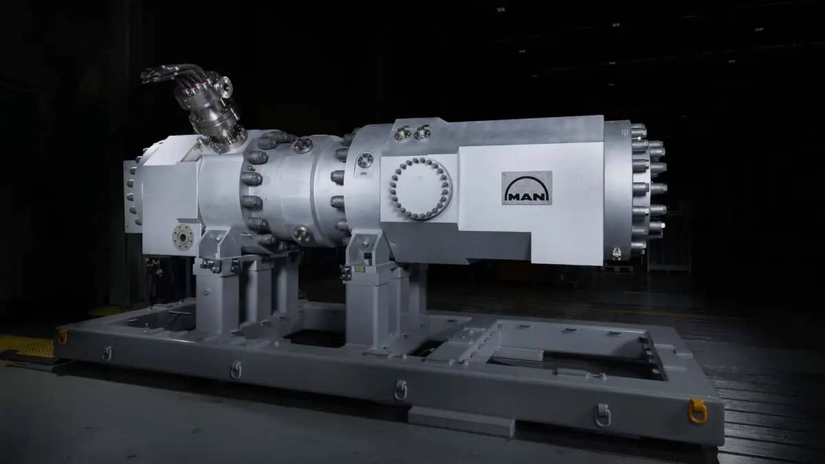 A large grey, metal engine-looking structure on a large platform in a dark room