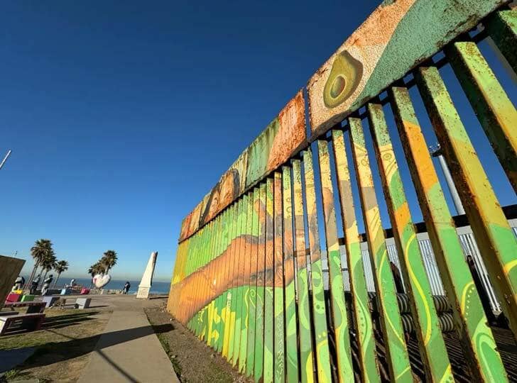 A green, yellow, and tan-colored painting on a border wall