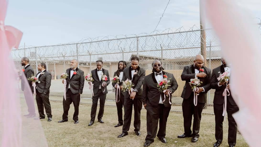 A row of men in tuxedos holding flower bouquets