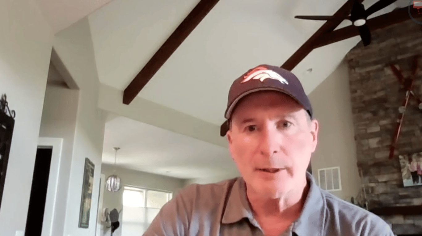 Screenshot of Don Cygan talking to a camera, his home visible behind him
