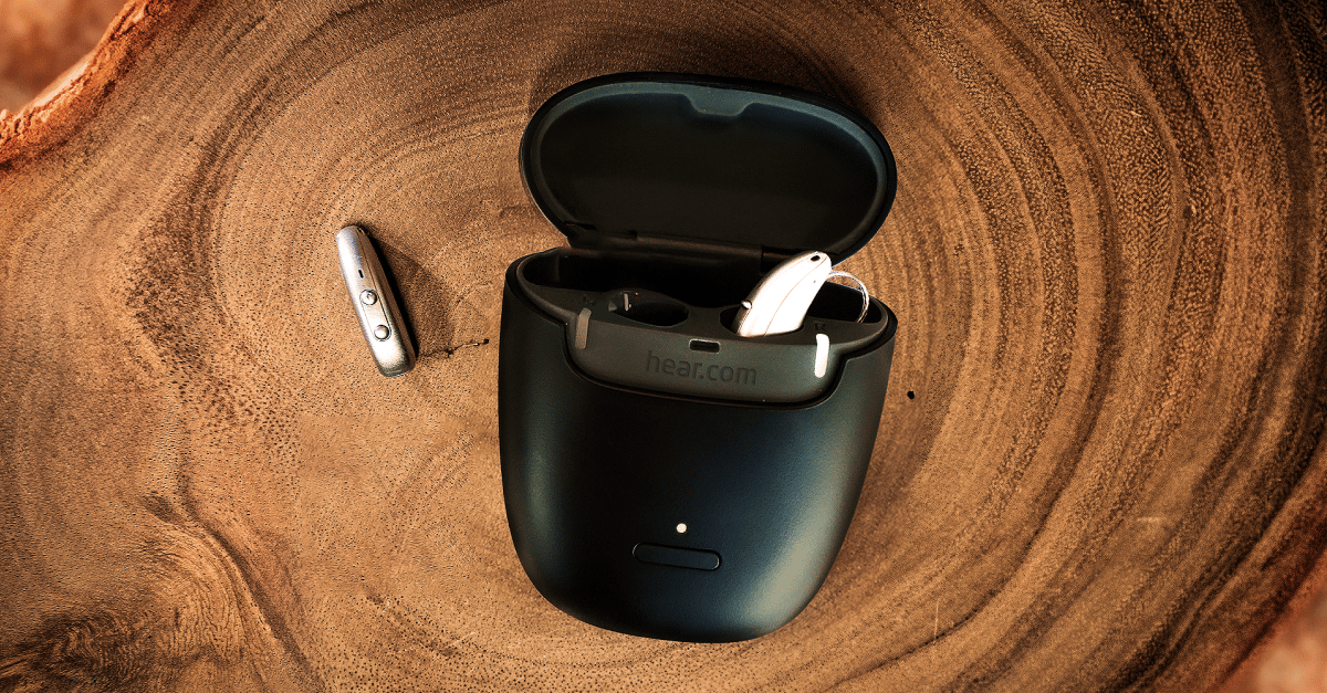 A black case with hearing aids in them sitting on a piece of wood