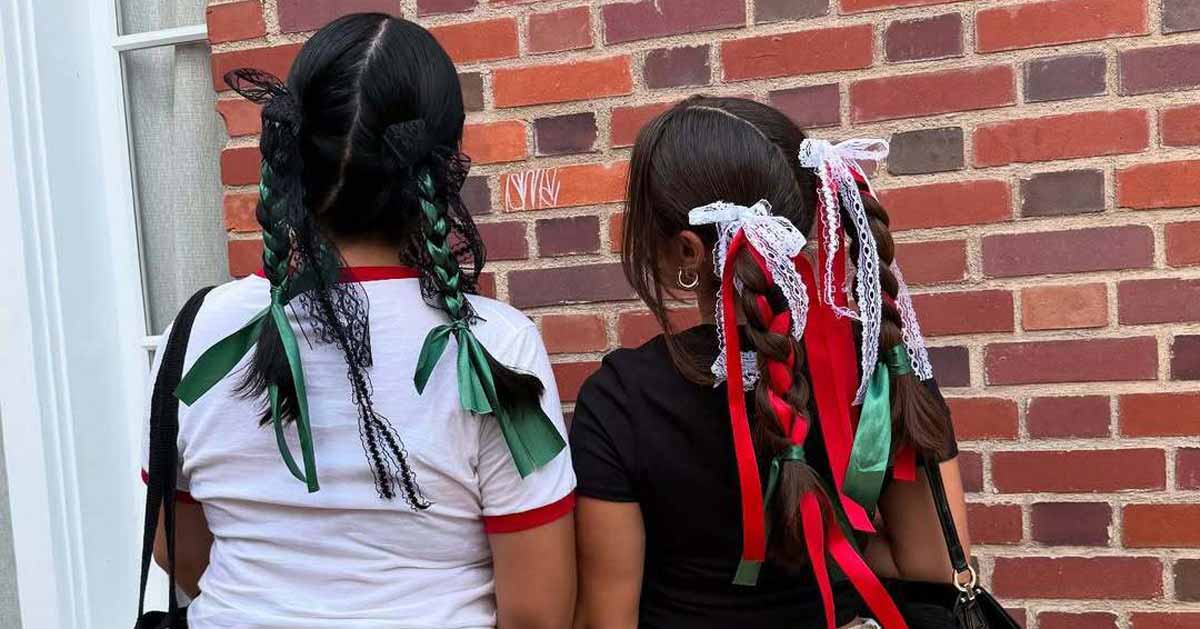 Two people showing the braids with colorful ribbons on their heads