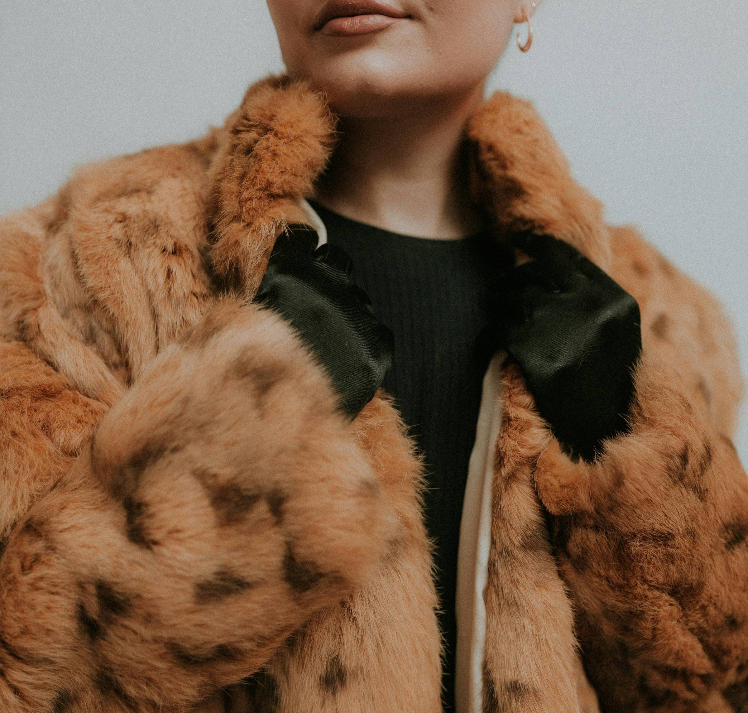 Person wearing black gloves and a red-brown fur coat