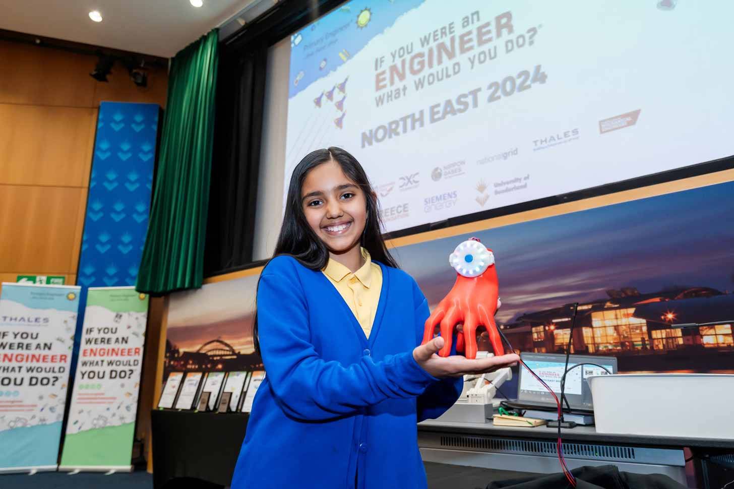 8-Year-old smiling with a model of her invention