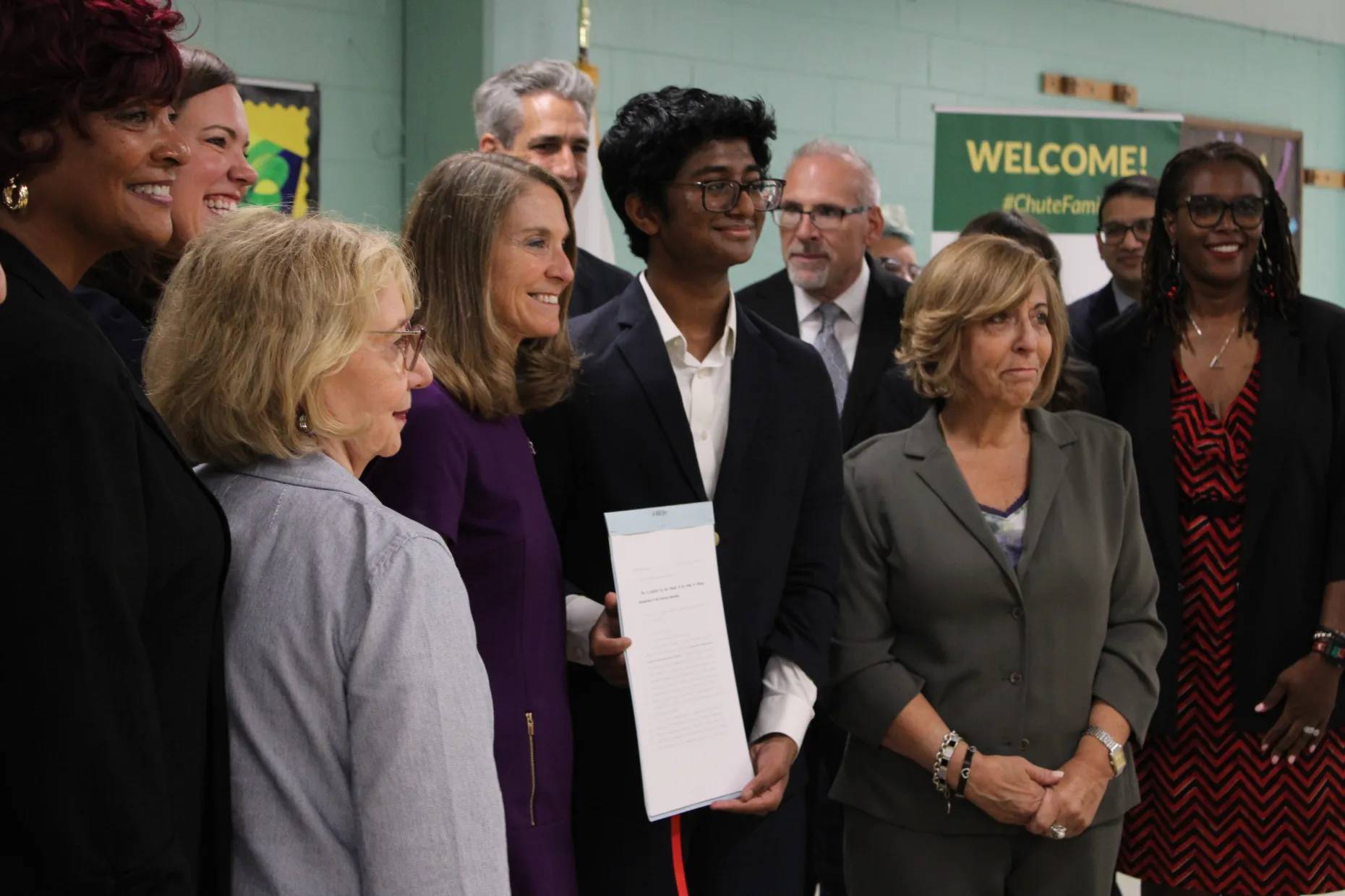 A group of people posing holding a signed bill