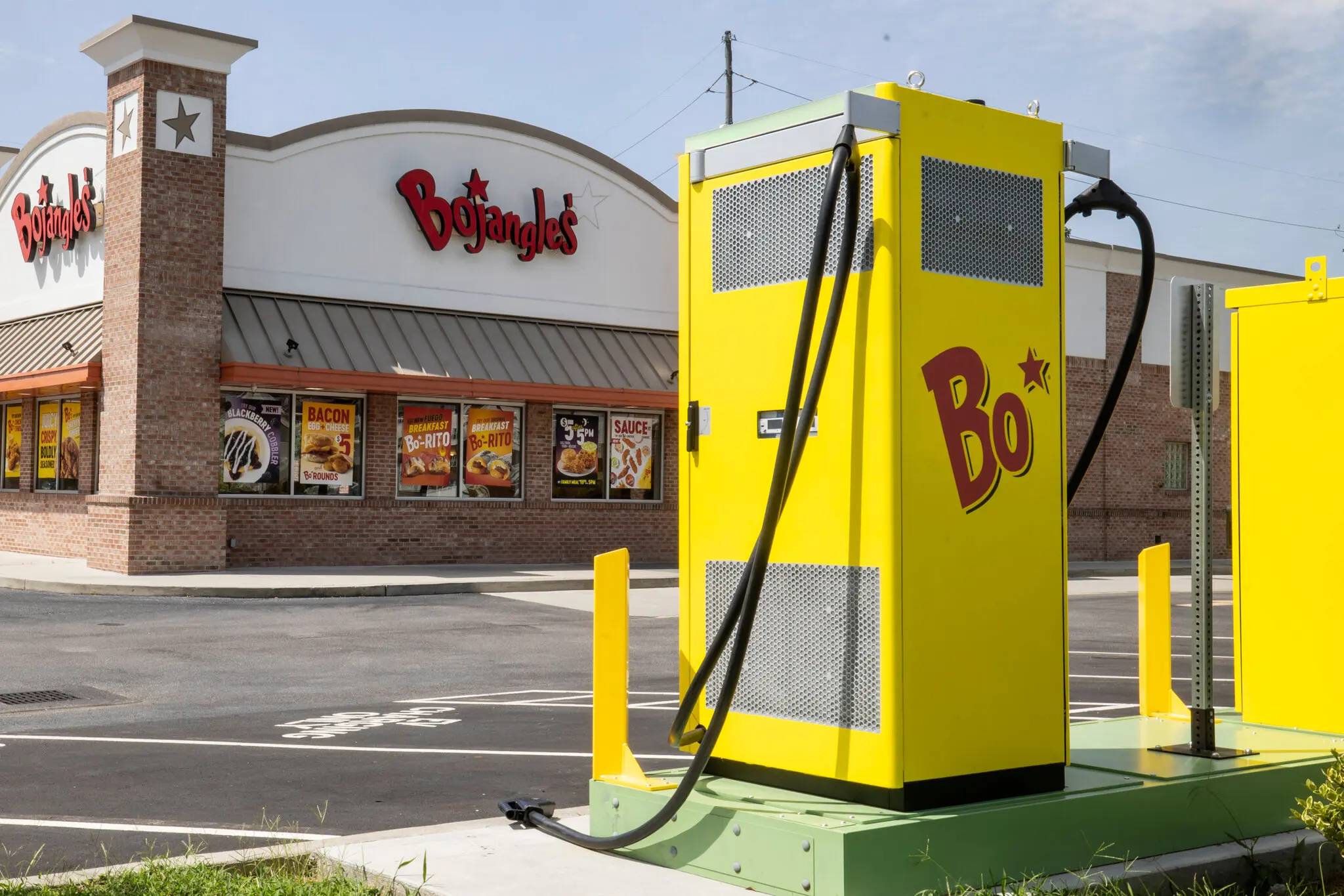 A yellow charging station in the parking lot of a Bojangles
