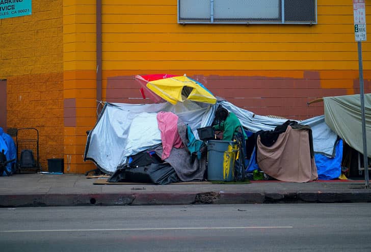 A homeless encampment at the side of a yellow building