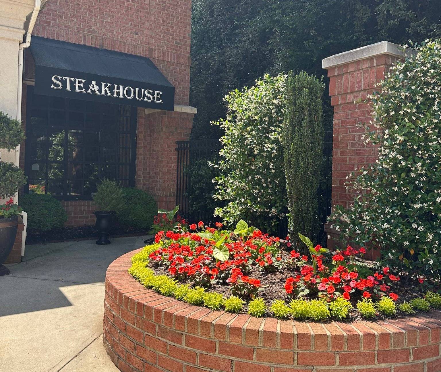 Exterior of a brick restaurant with "Steakhouse" on a black awning