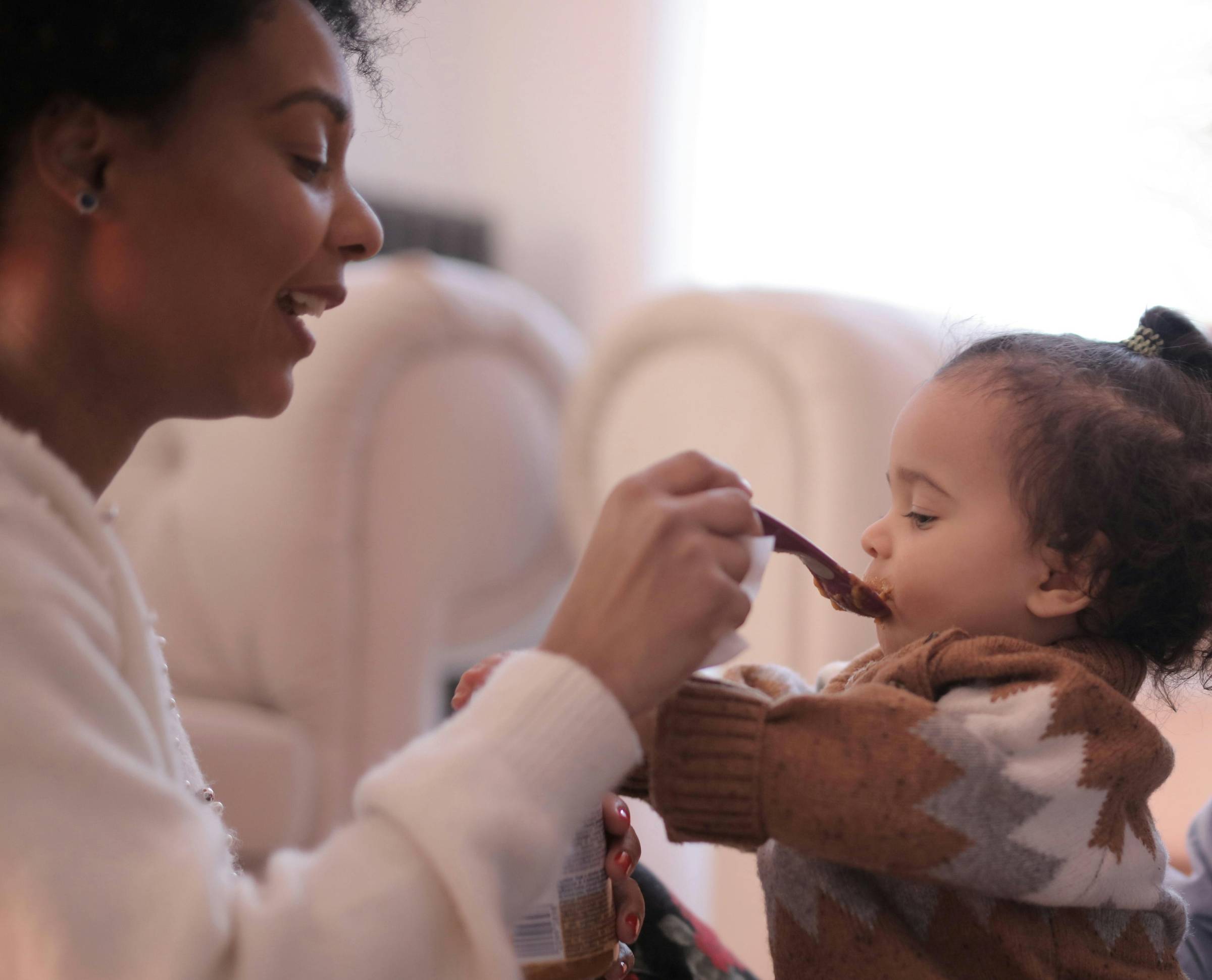 A mom feeding peanut butter to an older infant
