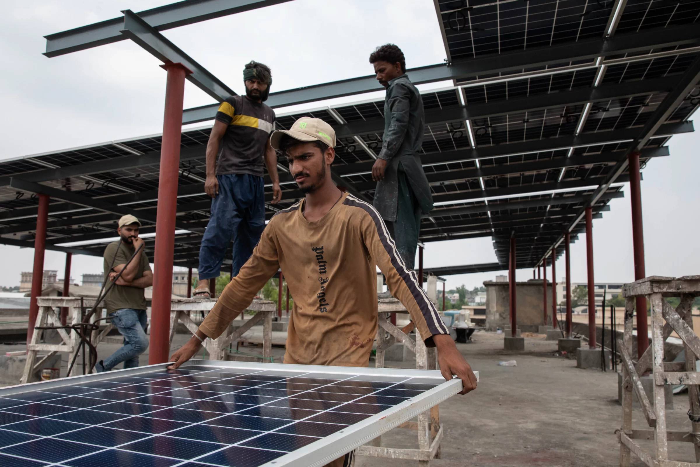 Four people installing solar panels on a metal roof structure