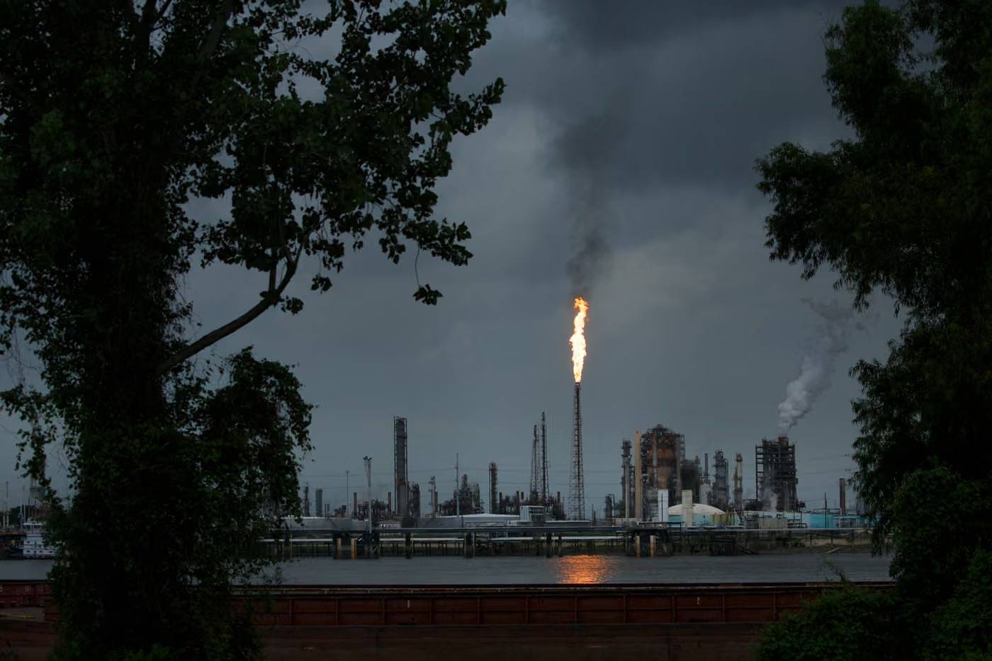 Fire shooting out of a tower against a dark, greying sky at a power plant
