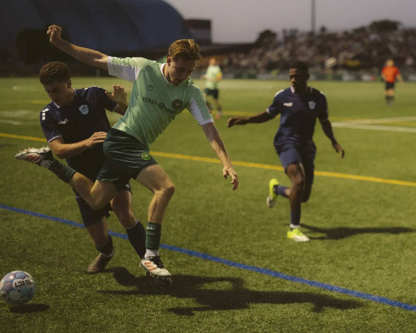 Three people vying for a soccer ball on a field