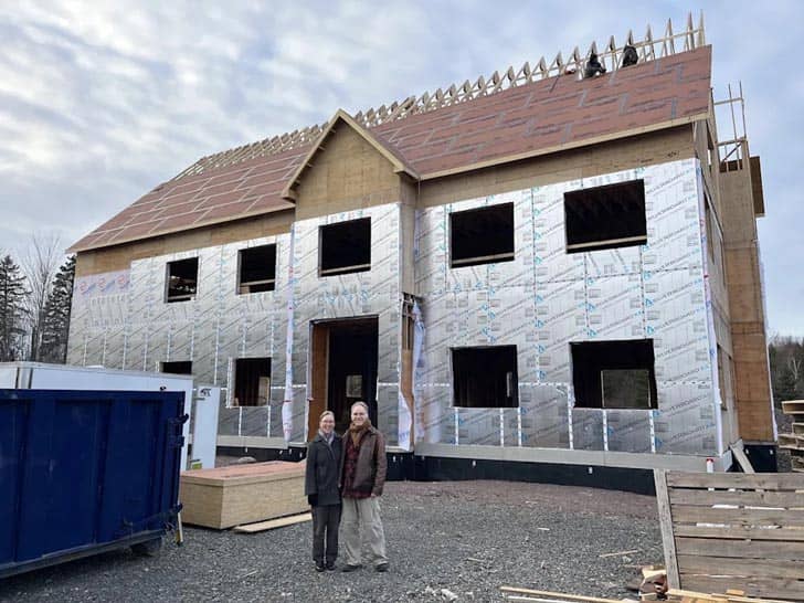 A couple standing together in front of a home that's under construction